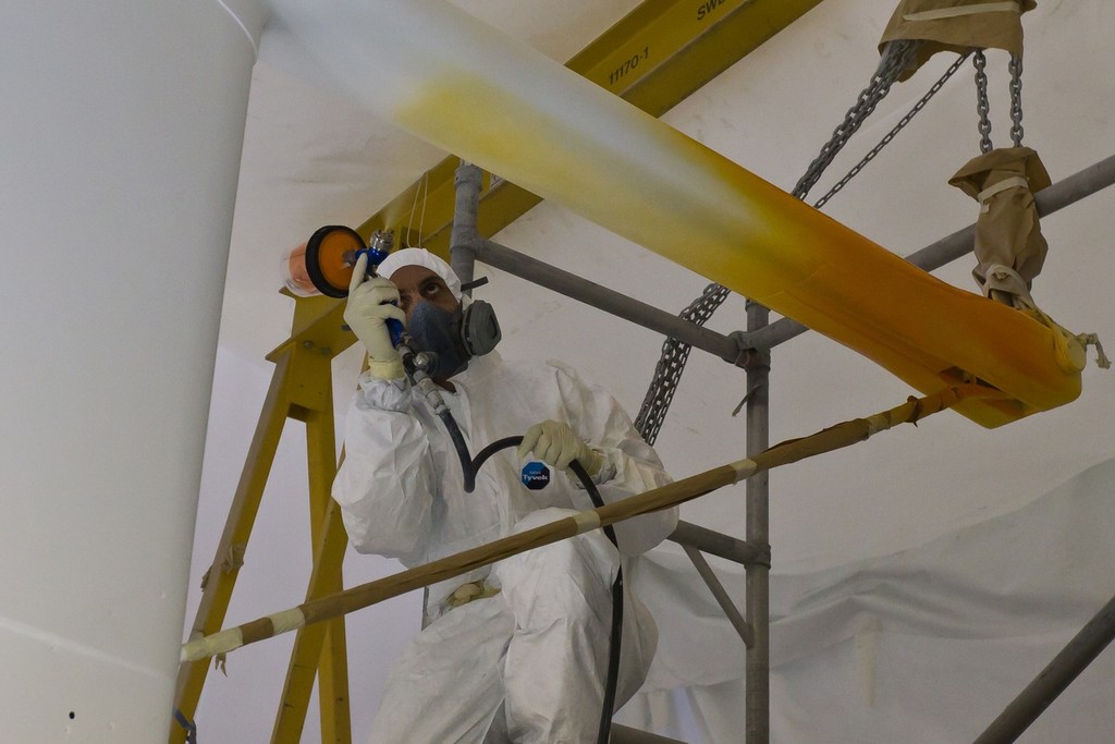 Painters spray the hull of Team Sanya at their base in Hamble, UK. Using high quality marine paint, each colour is sprayed on to masked areas, which will finally reveal the vibrant design.  © Volvo Ocean Race http://www.volvooceanrace.com