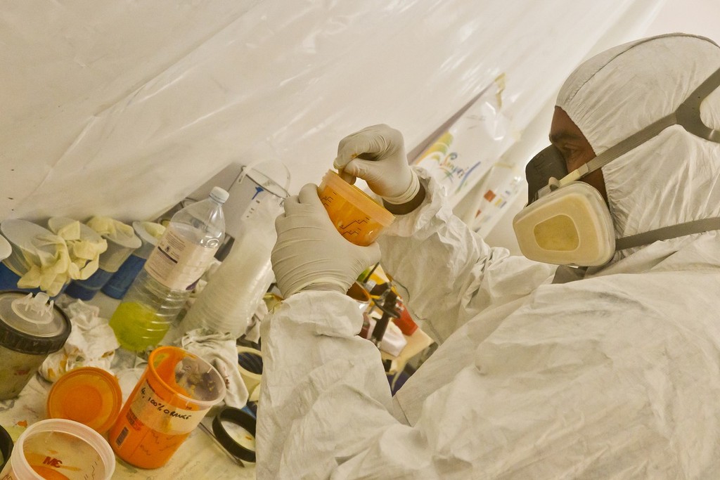 Painters spray the hull of Team Sanya at their base in Hamble, UK. Using high quality marine paint, each colour is sprayed on to masked areas, which will finally reveal the vibrant design.  © Volvo Ocean Race http://www.volvooceanrace.com