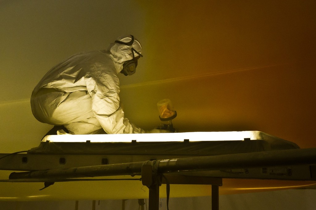 Painters spray the hull of Team Sanya at their base in Hamble, UK. Using high quality marine paint, each colour is sprayed on to masked areas, which will finally reveal the vibrant design.  © Volvo Ocean Race http://www.volvooceanrace.com