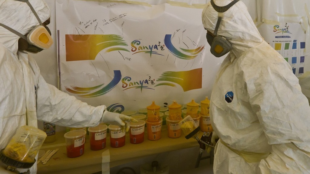 Painters spray the hull of Team Sanya at their base in Hamble, UK. Using high quality marine paint, each colour is sprayed on to masked areas, which will finally reveal the vibrant design.  © Volvo Ocean Race http://www.volvooceanrace.com