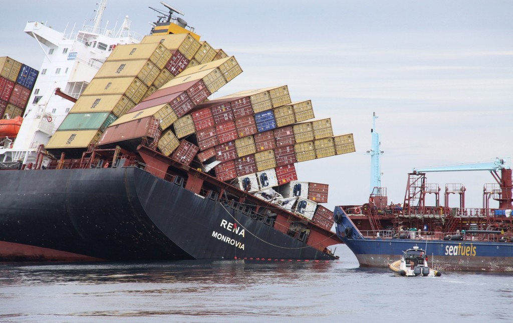 The grounded container ship Rena lists to starboard while the tanker ship Awanuia recieves the pumped oil off the ship. The line of orange buoys supports the oil pipeline between the two vessels.  © Maritime NZ www.maritimenz.govt.nz
