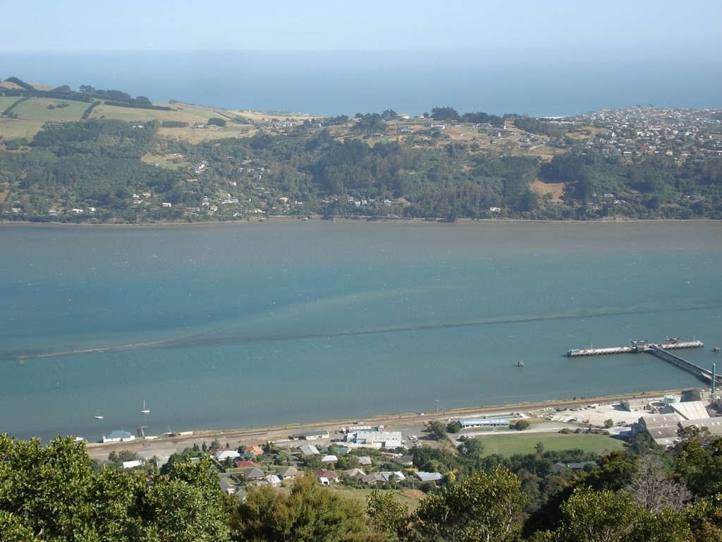 Ravensbourne Boating Club bottom left with the harbour’s rock wall - a now submerged wall built by the early settlers and running part of the length of Otago Harbour to force a channel up the western side of the harbour for shipping into Dunedin. © Colin Preston