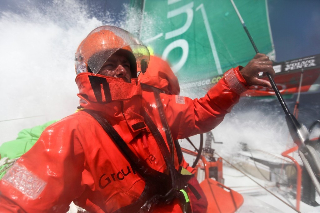 Laurent Pages shields himself from the onslaught of spray coming across the deck, onboard Groupama Sailing Team during leg 8 of the Volvo Ocean Race 2011-12, from Lisbon, Portugal to Lorient, France.  © Yann Riou/Groupama Sailing Team /Volvo Ocean Race http://www.cammas-groupama.com/