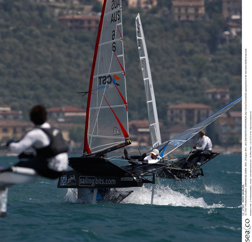 12_17357  ©Th.Martinez/Sea&Co.  CAMPIONE DEL GARDA - ITALY . 23 August  2012 . 
2012 ZHIK NAUTICA MOTH WORLDS. Day 5.
02-Joe Turner(AUS2) capzising front of  06- John Harris (AUS6) at top mark.
 photo copyright Th Martinez.com http://www.thmartinez.com taken at  and featuring the  class