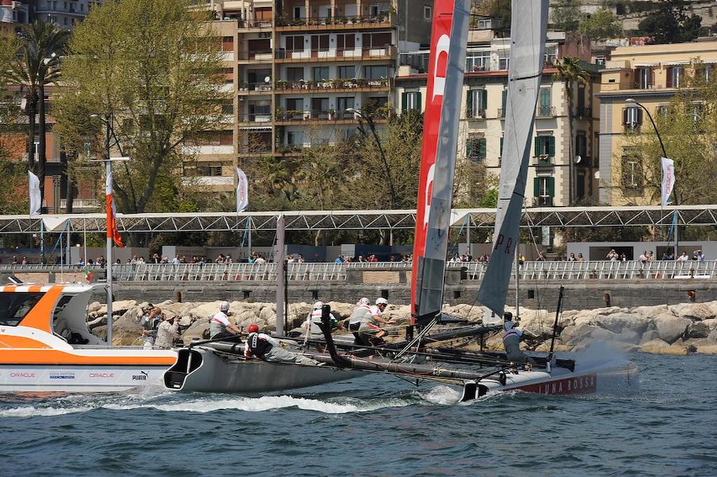 People on shore are able to watch Skipper Chris Draper sail Luna Rossa Piranha through the leeward gate and round the starboard Mark boat April 17, 2013 at an official practice race on the Bay of Napoli in Italy.  ©  SW