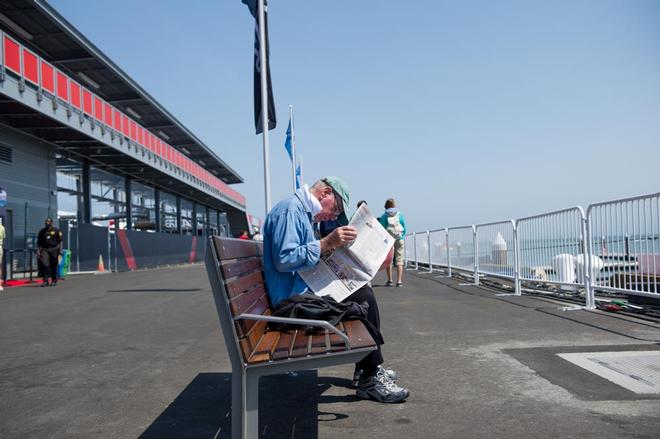 A man reads the morning paper down at the America’s park waiting for the days racing with only one boat.  © Paul Todd/Outside Images http://www.outsideimages.com
