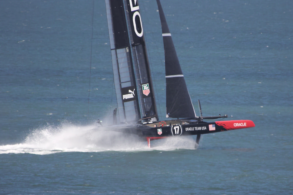 Oracle's crew gets yet another cold shower as the finned rudders and curved daggerboards dig in and lift the boat.  - America's Cup © Chuck Lantz http://www.ChuckLantz.com