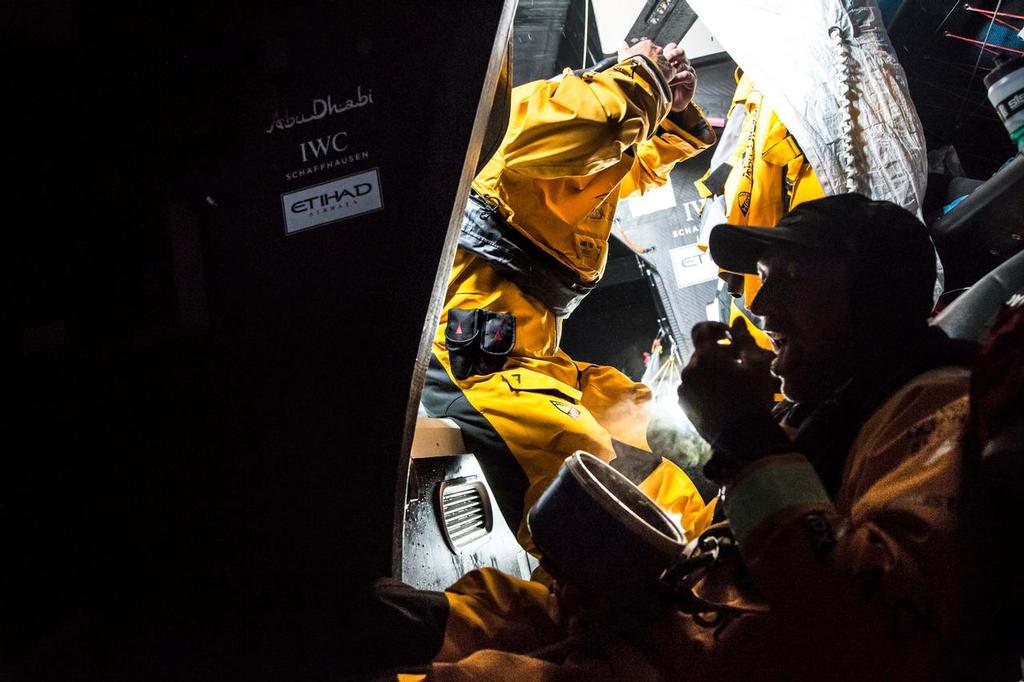 March 24, 2015. Leg 5 to Itajai onboard Abu Dhabi Ocean Racing. Day 06.  Justin Slattery takes a bite of a warm meal as he trades watches with Roberto Bermudez 'Chuny' behind him. © Matt Knighton/Abu Dhabi Ocean Racing