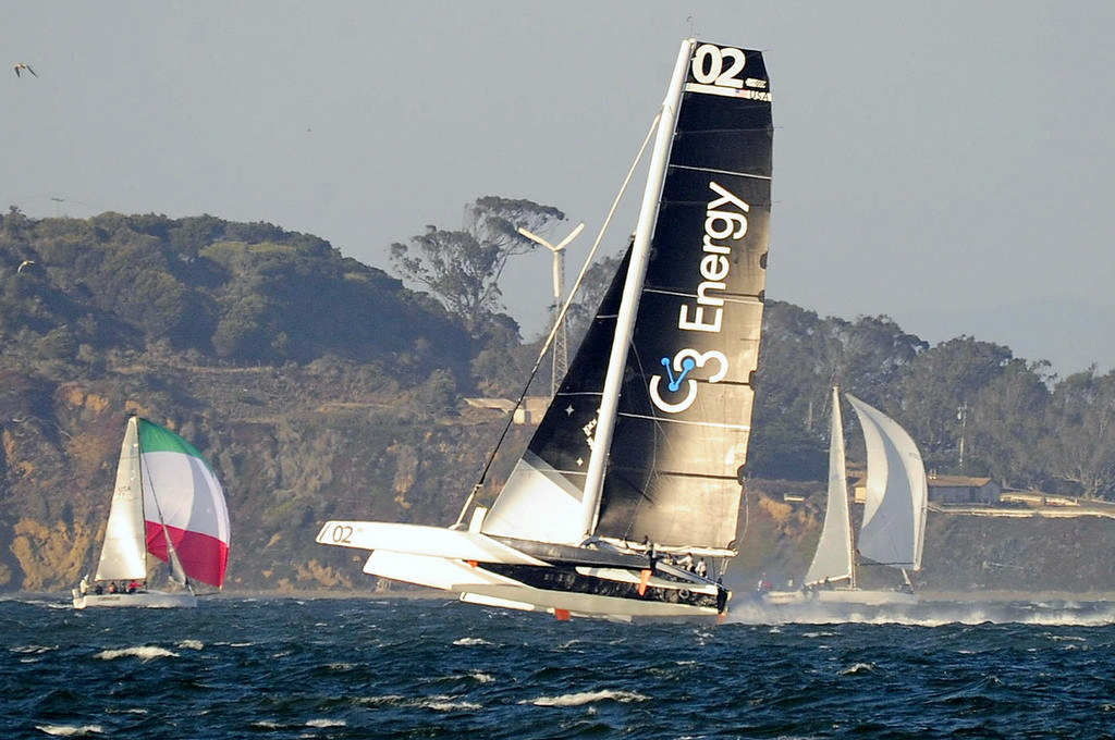 Tom Siebel's MOD70 trimaran Orion, scaring the hell out of a couple of monohulls, and probably themselves, when the wind amped-up late in the afternoon. FYI, the large propeller is an onshore wind generator and not a new secret weapon/accessory on the tri.  © Chuck Lantz http://www.ChuckLantz.com