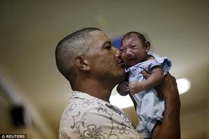 Women of child bearing age are being warned to consider trips to Brazil 'carefully' ahead of the Olympic Games this August. Pictured: Geovane Silva holds his son Gustavo Henrique, who has microcephaly - one of more than  4,000 babies to be born with the condition in the last 12 months photo copyright Reuters taken at  and featuring the  class