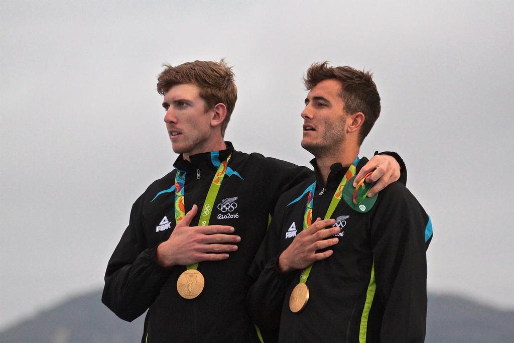 Blair Tuke and Peter Burling watch the NZ ensign raised at the 49er Medal ceremony - 2016 Olympic Sailing Regatta photo copyright Richard Gladwell www.photosport.co.nz taken at  and featuring the  class