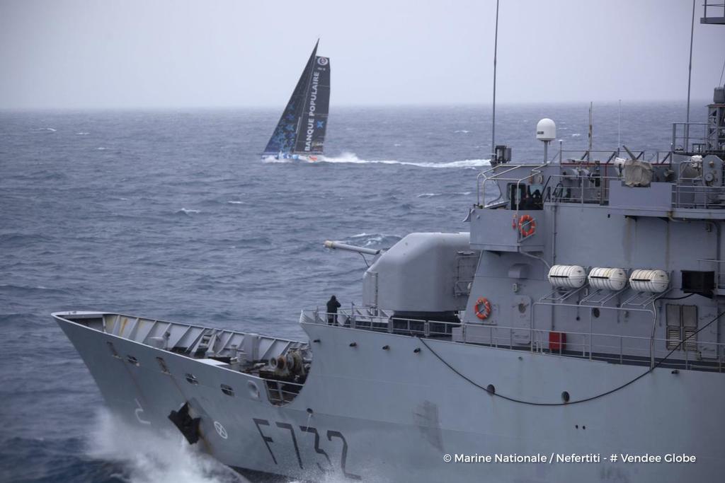 Banque Populaire VIII, skipper Armel Le Cleac’h (FRA), off the Kerguelen Islands, being over-flown over by a helicopter from the National French Marine Nivose Frigate, during the Vendee Globe, solo sailing race around the world, on November 30th, 2016 photo copyright Marine Nationale / Nefertiti / Vendee Globe vendeeglobe.org taken at  and featuring the  class