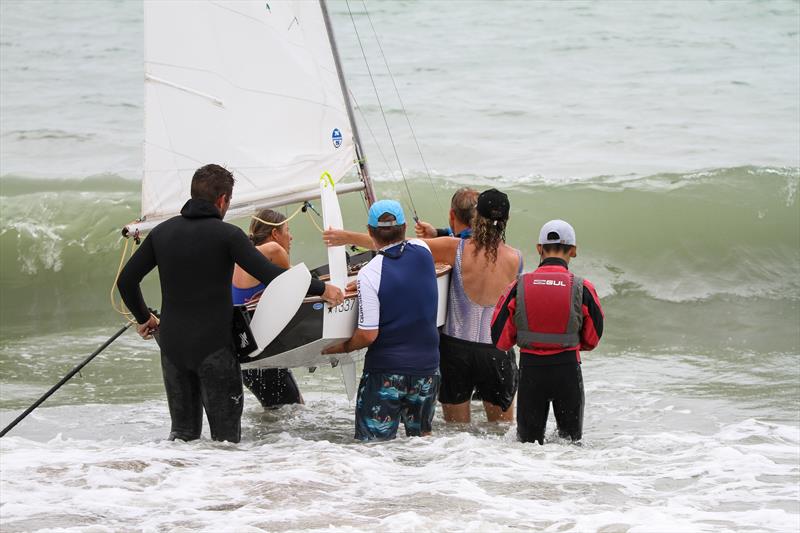 One of the 180 boat fleet launch into surf - the sailor is in the red jacket on the right - Wakatere BC - Optimist and Starling Auckland - February 6, 2022 - Day 2 photo copyright Richard Gladwell / Sail-World.com / nz taken at Wakatere Boating Club and featuring the Starling class